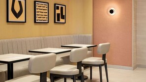 Een restaurantinterieur met een zithoek met tafels en stoelen.