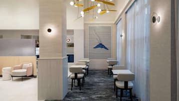 A hotel lobby with a reception desk, seating area, and a large wall art piece.