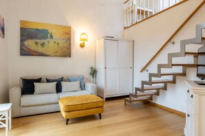 A living room with a sofa, ottoman, and a painting on the wall. - San Frediano Panoramic Terrace (Firenze)