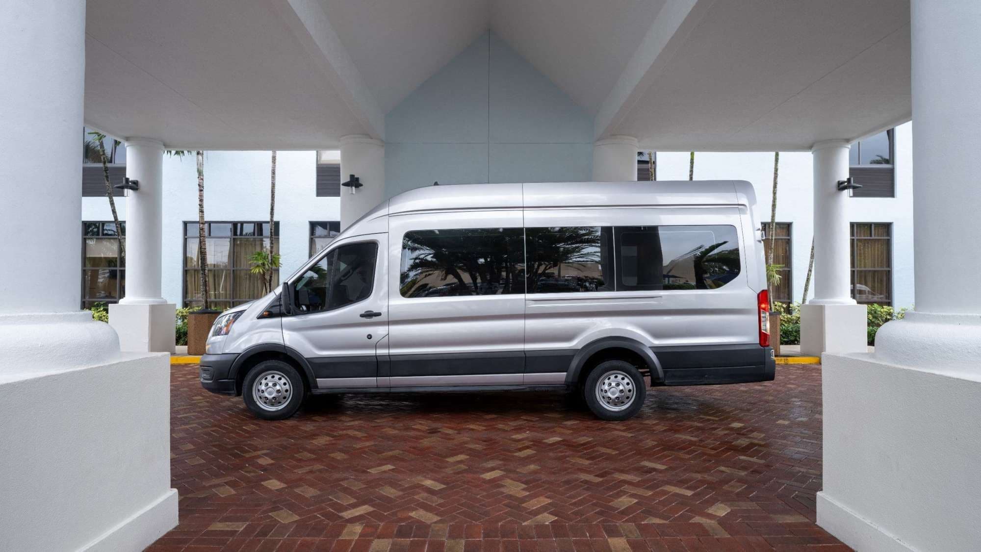 A silver van parked under a covered area with a brick floor.