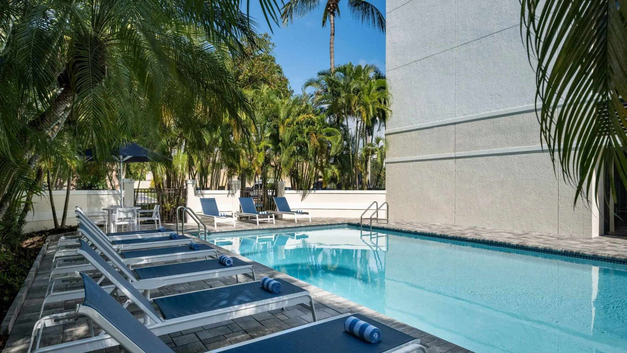 A pool area with lounge chairs and a clear blue pool.