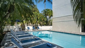 A pool area with lounge chairs and a clear blue pool.