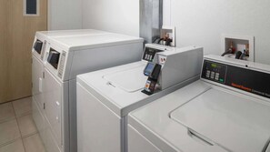 Une laverie équipée de deux machines à laver à chargement frontal, d’un panneau de commande et d’un terminal de paiement.