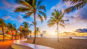 Ein Strand mit Palmen, einem Rettungsturm und einer gewundenen Promenade.