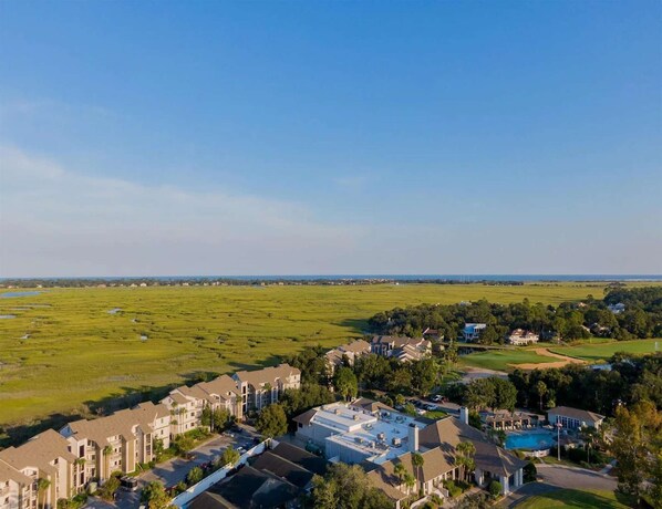 A residential area with apartment buildings, a swimming pool, and a golf course in the background.