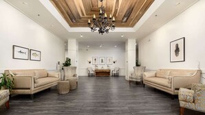 A spacious lobby with two sofas facing each other, a chandelier, and framed artwork on the walls. - Marshlands Views + Golf Course. Pool. Restaurant. (St. Simons Island)