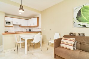 Una cocina moderna con armarios blancos, una encimera de madera y un comedor con sillas blancas.