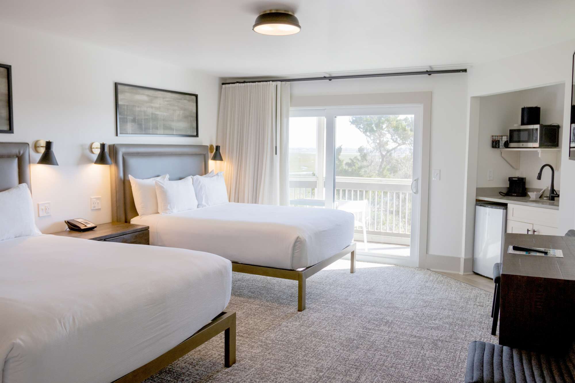 Une chambre d’hôtel avec deux lits, un bureau équipé d’un micro-ondes et un balcon avec vue.