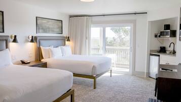 Une chambre d’hôtel avec deux lits, un bureau équipé d’un micro-ondes et un balcon avec vue.