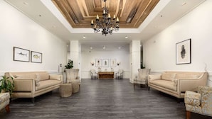 A spacious lobby with two sofas facing each other, a chandelier, and framed artwork on the walls. - Direct Marshlands Views + Golf. Pool. Restaurant. (St. Simons Island)