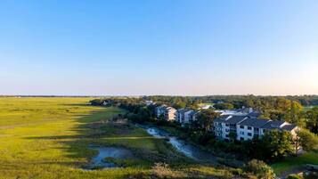 Una zona residencial con varias casas de dos pisos, un río y un amplio campo verde.