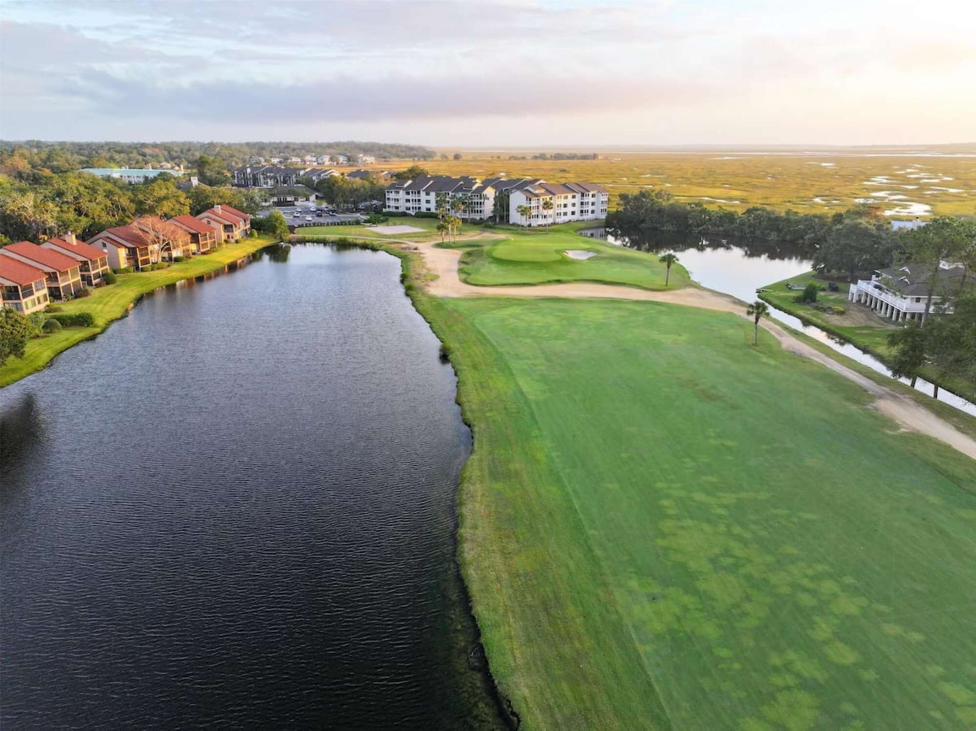 Un parcours de golf avec un plan d’eau, entouré de bâtiments résidentiels.