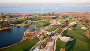 An aerial view of a golf course with multiple greens, water hazards, and a large body of water. - Direct Golf Course Access + Pool. Dining. Shuttle. (St. Simons Island)