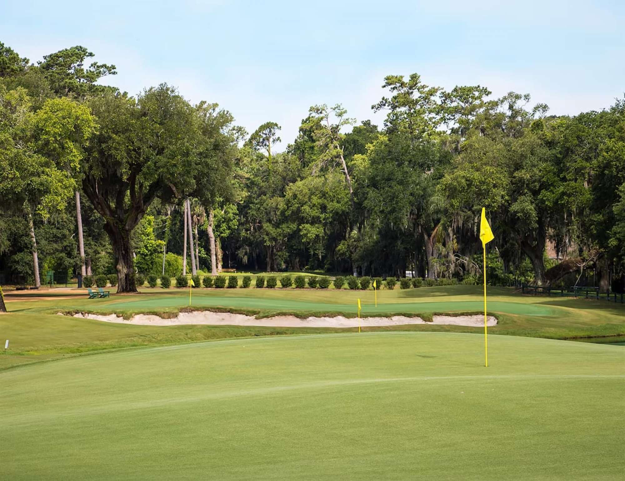 A golf course with a well-maintained green, sand bunkers, and a flagstick.