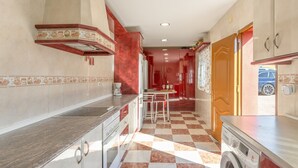 Una cocina con piso a cuadros, lavadora y comedor con mesa y sillas.