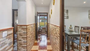 Un pasillo con piso a cuadros, un comedor con mesa y sillas, y una estatua en la pared.
