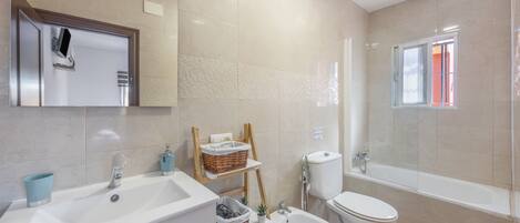 A modern bathroom with a sink, bidet, toilet, and bathtub.