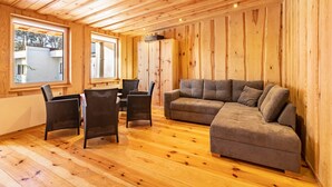 A wooden-paneled room with a sofa, chairs, and a window.
