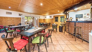 A restaurant with wooden ceiling, multiple tables, and chairs.