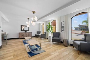A modern hotel lobby with a wooden floor, a reception desk, a large mirror, and a seating area with sofas and chairs. - Walk to Santa Cruz Beach | Free Breakfast + Pool (Santa Cruz)