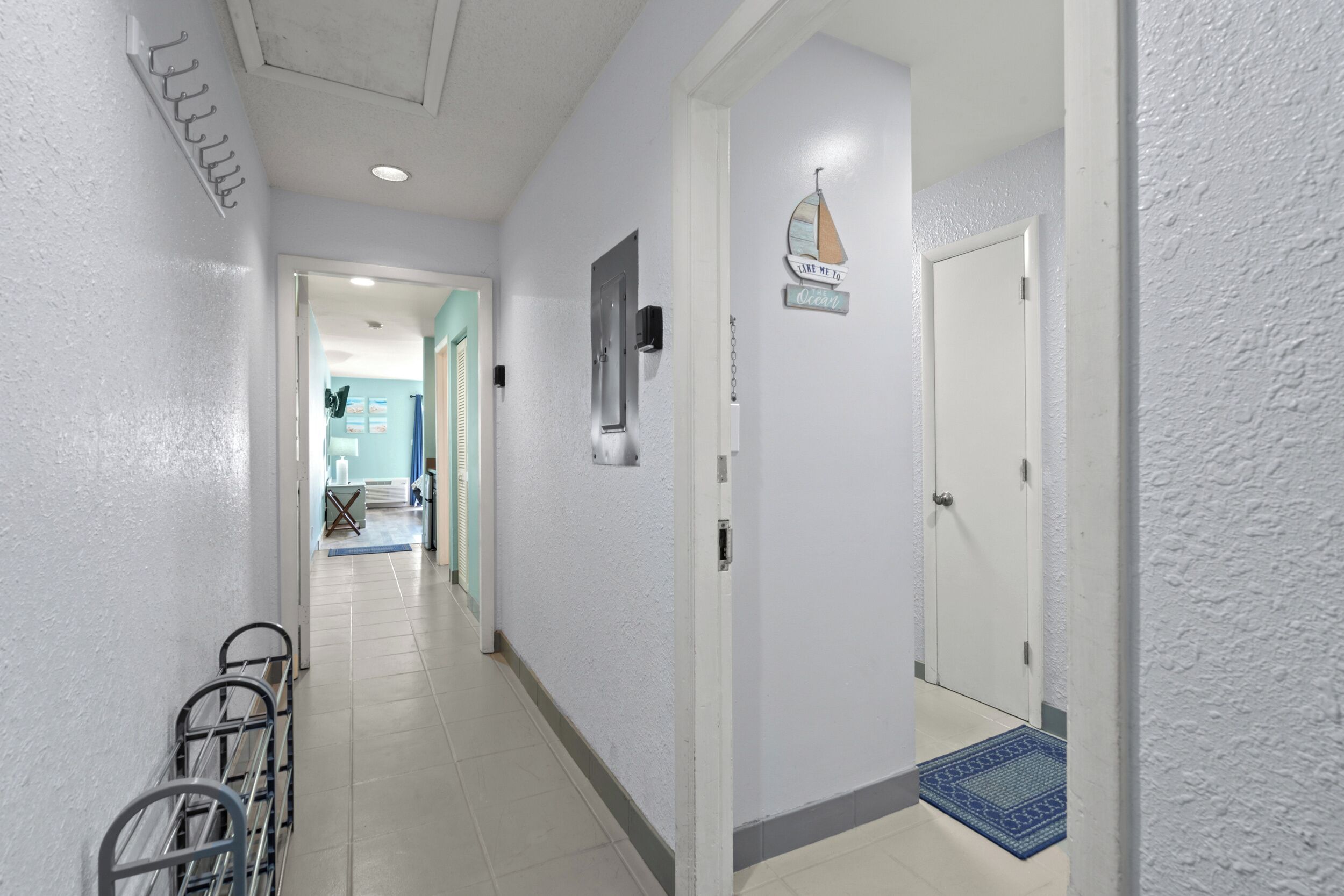A hallway with a metal rack, a door with a sign, and a blue mat.