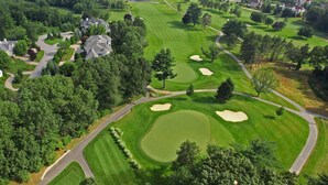 A golf course with well-maintained greens, sand bunkers, and a clubhouse in the background. - Near Merrimack College + Free Breakfast. Pool. Gym (Andover)