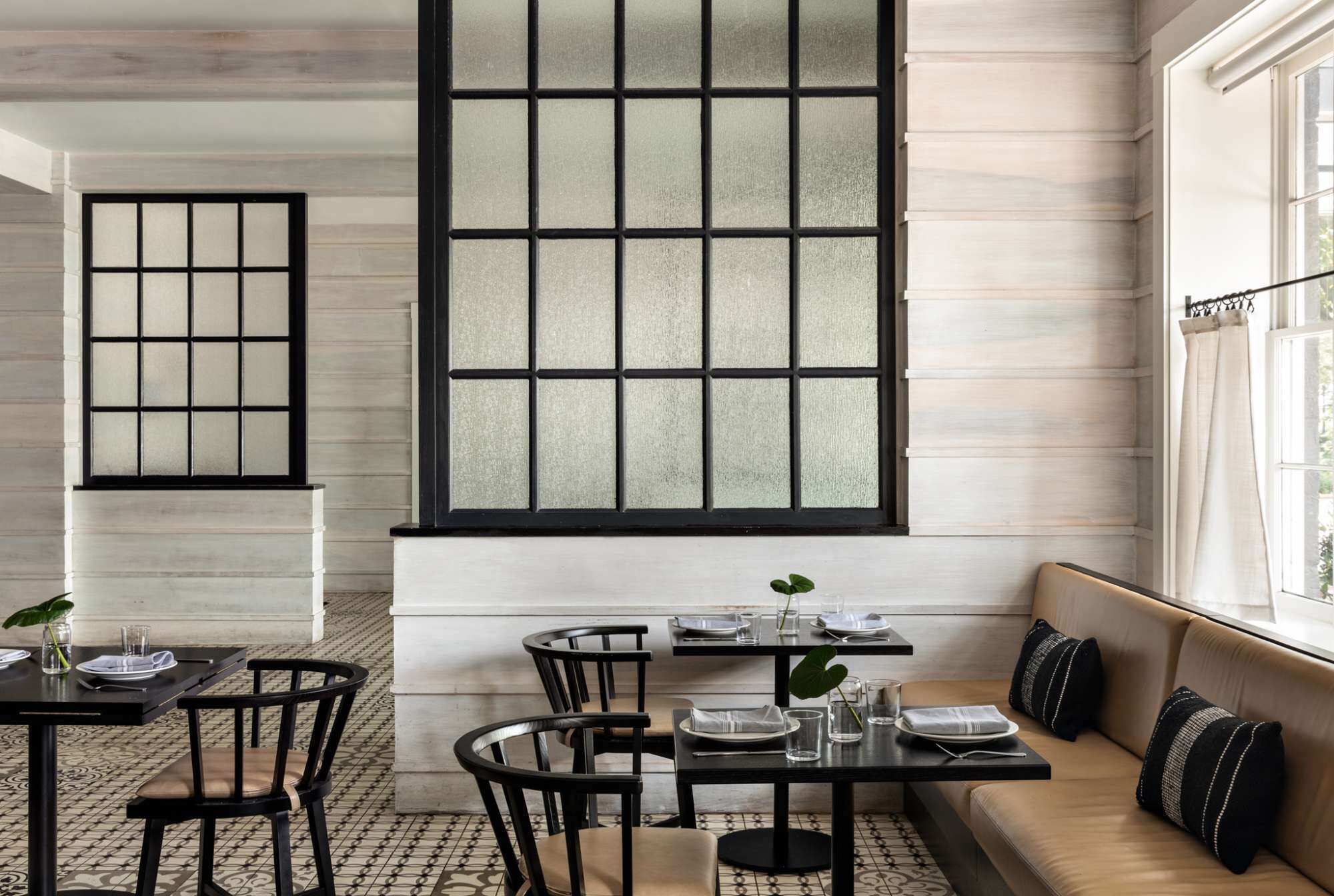 A dining area with a large window, a sofa, and a table set for two.