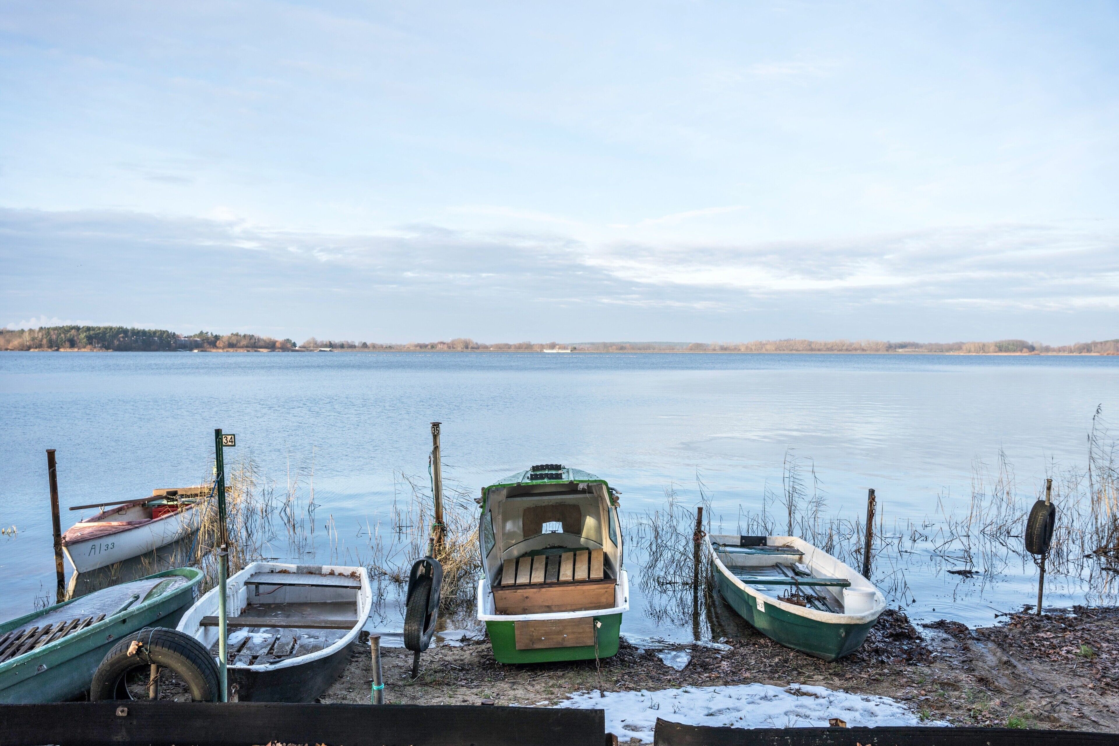 A lakeside view with boats docked along the shore.