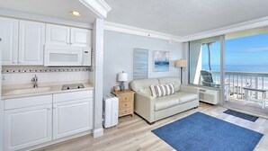 A compact living space with a kitchenette, a sofa, a coffee table, and a view of the ocean. - Oceanfront •Private Balcony •Overlooks Heated Pool (Daytona Beach)