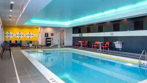 An indoor swimming pool with a tiled floor, red chairs, and a yellow wall with circular patterns. - Near to Riverwalk | Indoor Pool + Free Breakfast (Naperville)