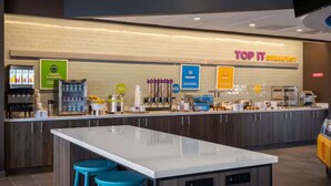 A modern breakfast area with a counter, stools, and various food and beverage dispensers. - Near to Riverwalk | Indoor Pool + Free Breakfast (Naperville)