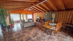 Un vaste espace de vie comprenant un canapé, une table à manger et des chaises, des murs en bois et un sol carrelé.