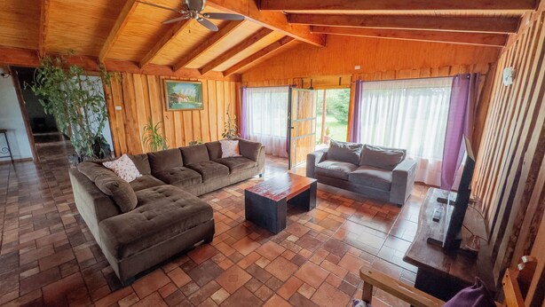Un salon spacieux doté d’un plafond en bois et d’une grande fenêtre.