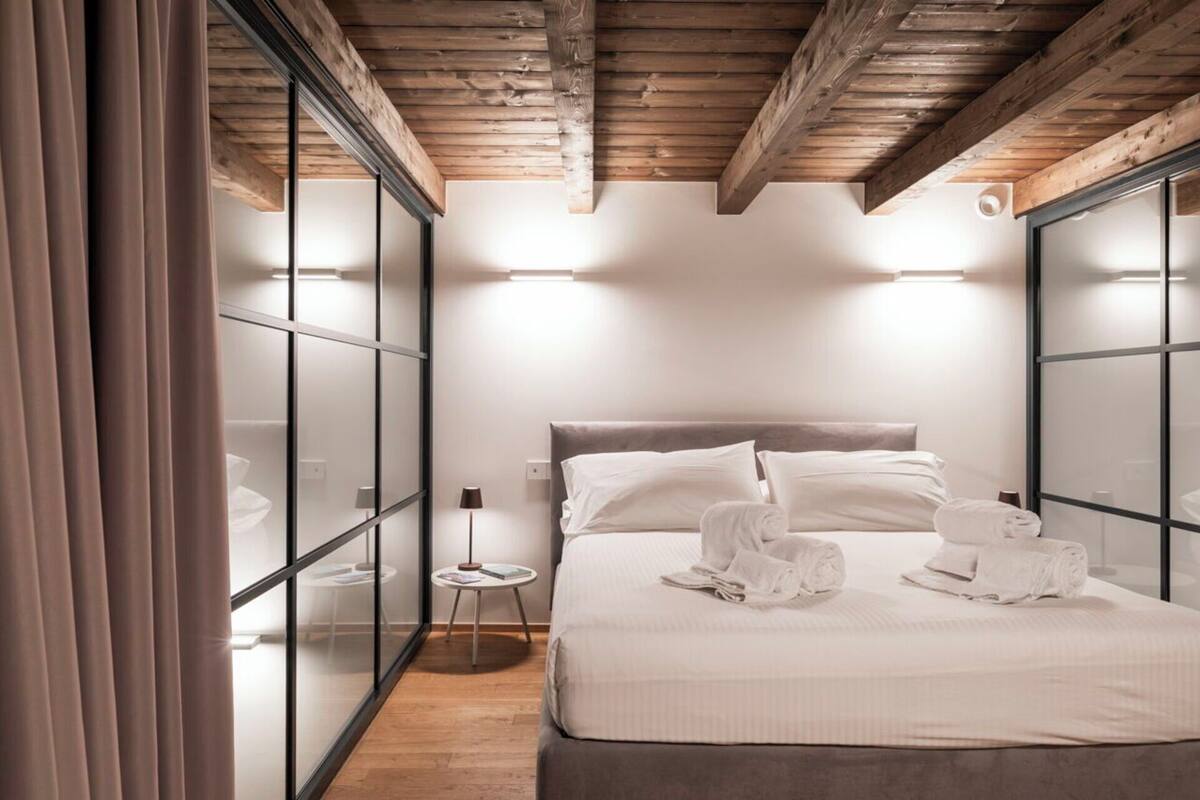 A modern bedroom with a bed, bedside tables, and a small round table.