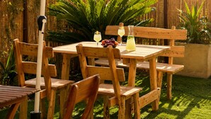 Una taula de fusta amb caires, una tanca de bambú i una zona enjardinada.