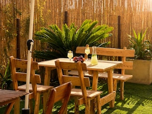 A wooden table with chairs, a bamboo fence, and a grassy area. - Dream Appartment Jardins Carthage (Tunis)