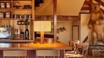 A rustic interior with a wooden bar, seating, and a bear statue.