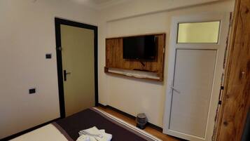 A room with a bed, a television mounted on the wall, a door, and a window.