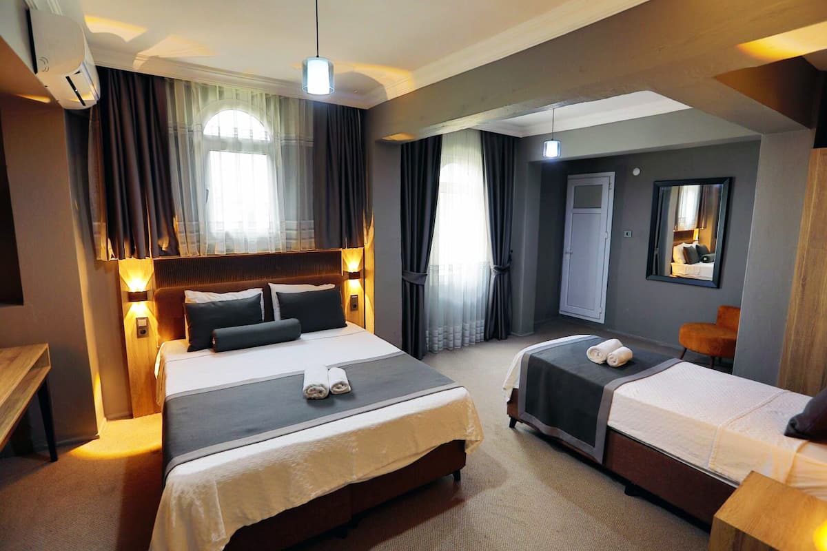 Une chambre d’hôtel avec deux lits, un bureau, une chaise, un miroir et une armoire.