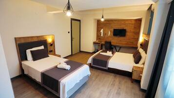 Habitación de hotel con dos camas, un escritorio, una silla, un televisor y una pared decorativa de madera.