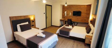 A hotel room with two beds, a desk, a chair, a TV, and a wooden accent wall.