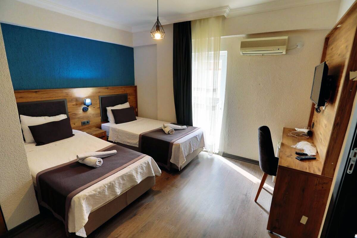 Une chambre d’hôtel avec deux lits, un bureau, une chaise et un téléviseur.