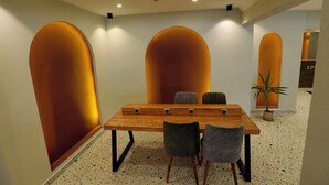 A conference room with a wooden table and chairs, arched wall designs, and a speckled floor. - Ida Efes Hotel (Selcuk)