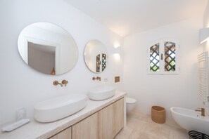 Une salle de bain moderne avec deux grands lavabos, des toilettes et un bidet.