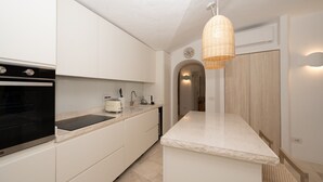 A modern kitchen with white cabinetry, a built-in oven, a sink, and a hanging light fixture.