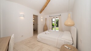 Un dormitorio con cama, mesita de noche, lámpara colgante y vistas al exterior.