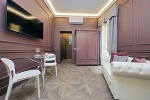 A modern living room with a flat-screen TV, a dining table with chairs, a white sofa, and a large wardrobe. - Suite Butterfly -Porpora (Roma)