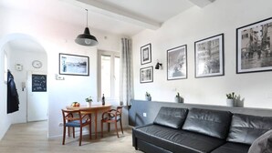 A modern living room with a black leather sofa, a wooden dining table with chairs, and framed black and white photographs on the wall. - Florence Central Market (Firenze)
