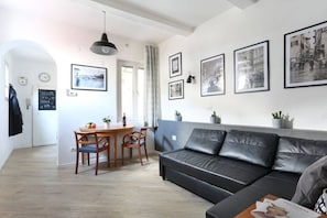 A modern living room with a black leather sofa, a wooden dining table with chairs, and framed black and white photographs on the wall. - Florence Central Market (Firenze)