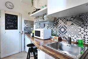 A kitchen with a chalkboard sign, patterned tiles, a microwave, a sink, and bar stools. - Florence Central Market (Firenze)